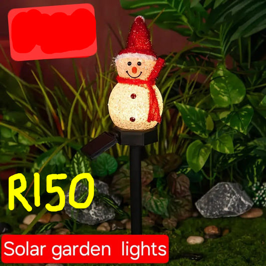 Solar garden light shaped like a snowman with a red hat and scarf, surrounded by greenery.